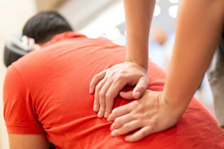 Adult seated safely while a clinician assesses neck movement and balance during a vertigo evaluation.