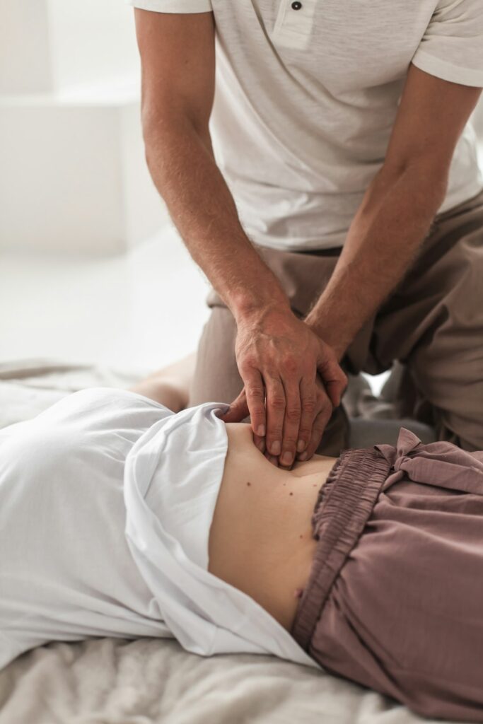 Person resting with a towel-wrapped ice pack on the lower back beside a heating pad.