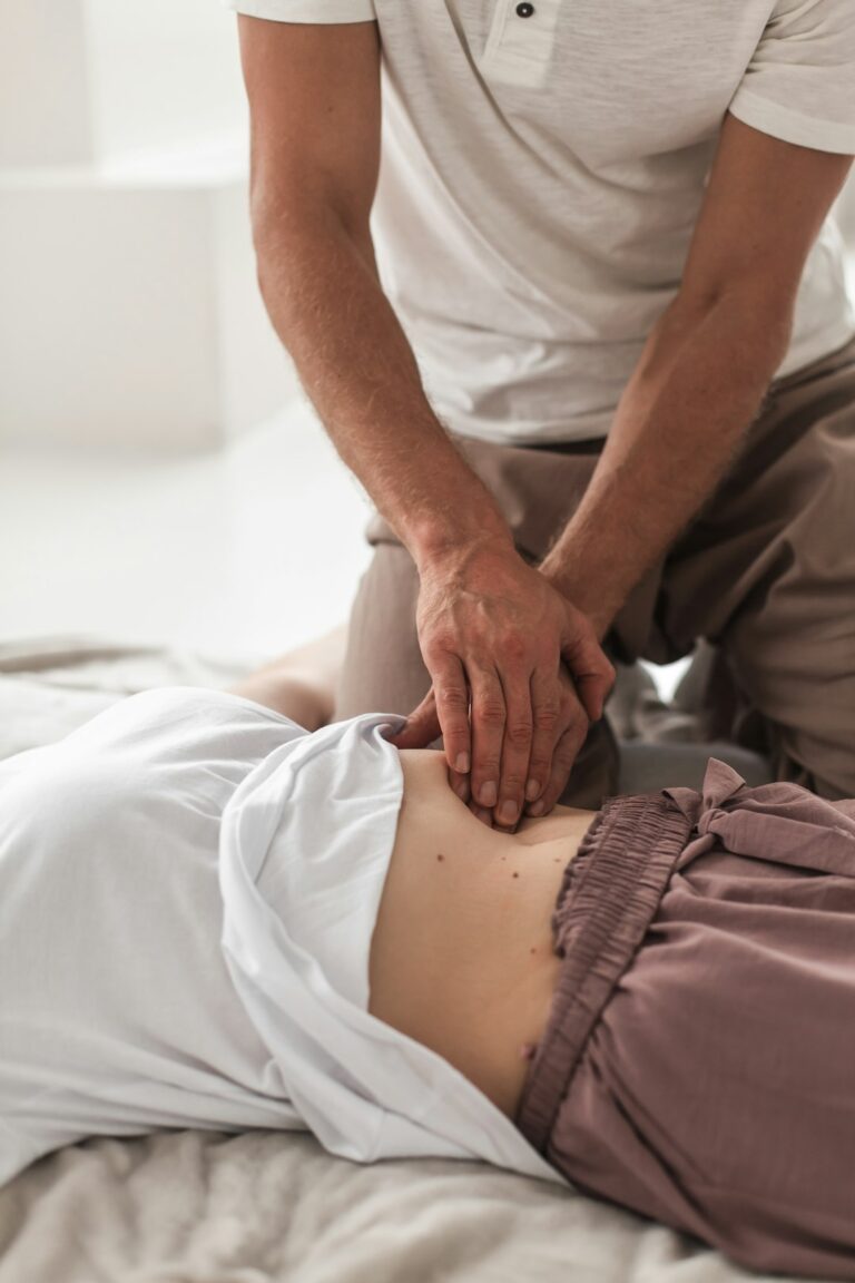 Person resting with a towel-wrapped ice pack on the lower back beside a heating pad.